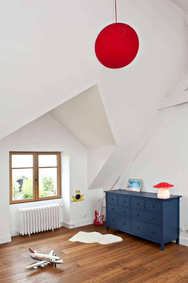 Modern inredning av ett mellanstort pojkrum kombinerat med lekrum och för 4-10-åringar, med vita väggar och mellanmörkt trägolv