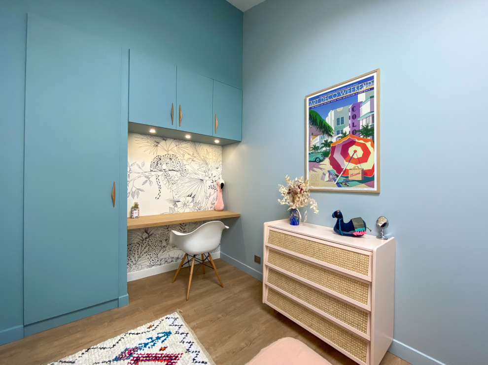 Diseño de dormitorio infantil actual de tamaño medio con escritorio, paredes azules, suelo beige y suelo de madera clara
