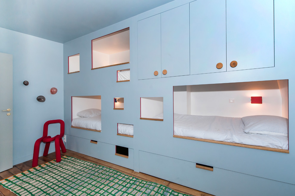 Cette photo montre une chambre d'enfant tendance avec un mur bleu, un sol marron et un lit superposé.