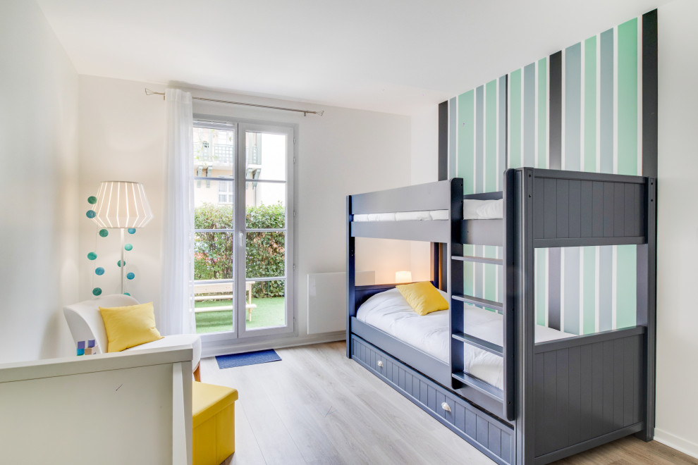 Minimalistisk inredning av ett mellanstort könsneutralt barnrum kombinerat med sovrum och för 4-10-åringar, med gröna väggar, laminatgolv och brunt golv