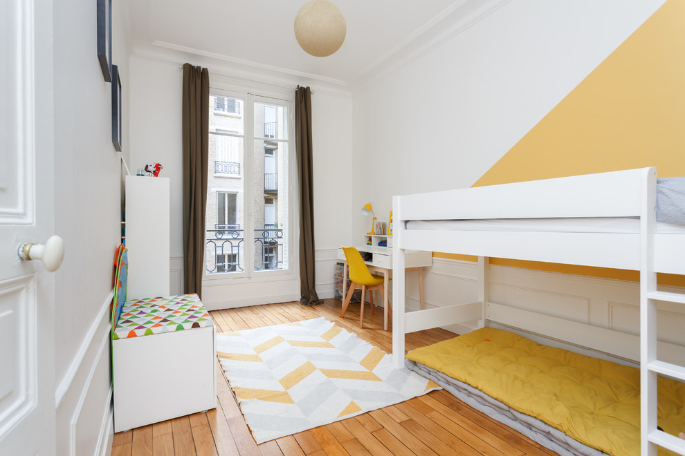 Cette image montre une chambre d'enfant de 4 à 10 ans nordique de taille moyenne avec un sol en bois brun, un mur jaune et un sol marron.