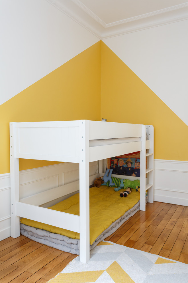 Ispirazione per una cameretta per bambini da 4 a 10 anni scandinava di medie dimensioni con pareti gialle, pavimento in legno massello medio e pavimento marrone