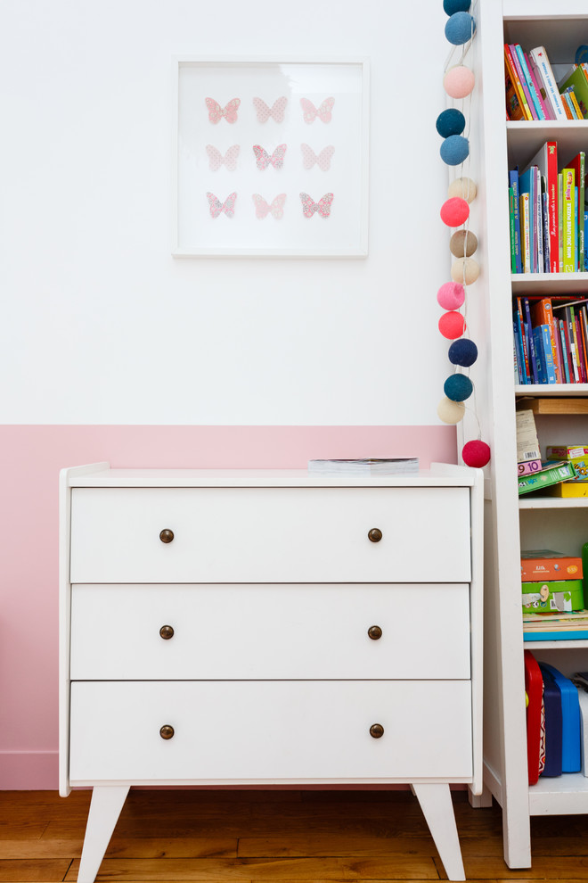 Modelo de dormitorio infantil de 4 a 10 años nórdico de tamaño medio con paredes rosas, suelo de madera en tonos medios y suelo marrón
