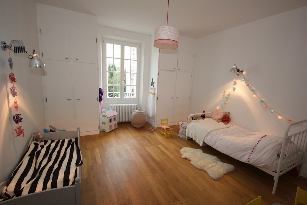 Kids' room - contemporary gender-neutral light wood floor kids' room idea in Toulouse with white walls
