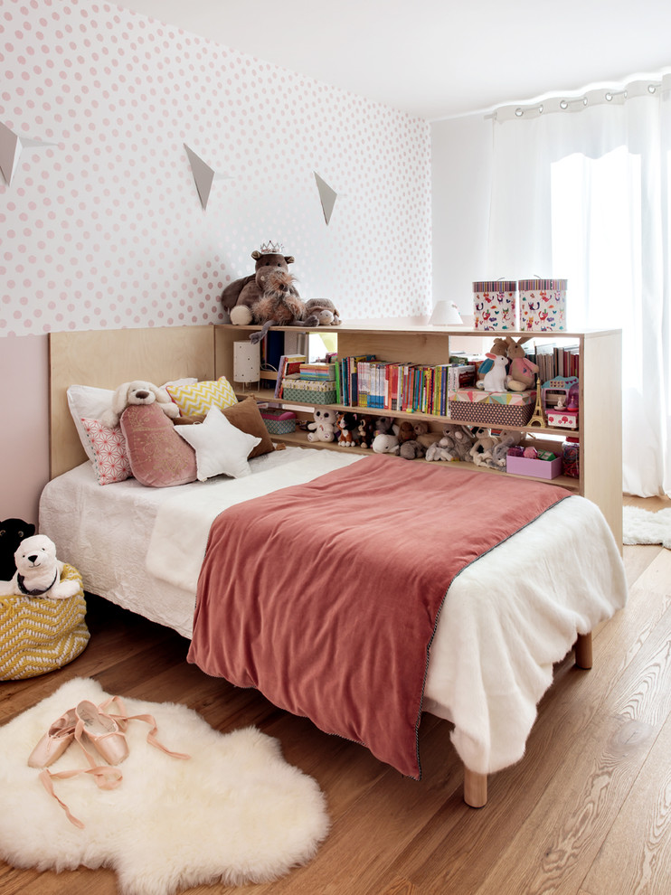 Modelo de dormitorio infantil contemporáneo con paredes rosas, suelo de madera en tonos medios y suelo marrón