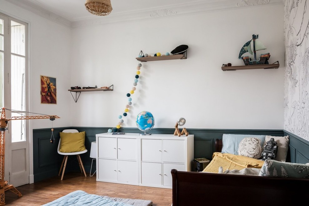 Large scandi children’s room for boys in Paris with brown floors, white walls, medium hardwood flooring and a dado rail.