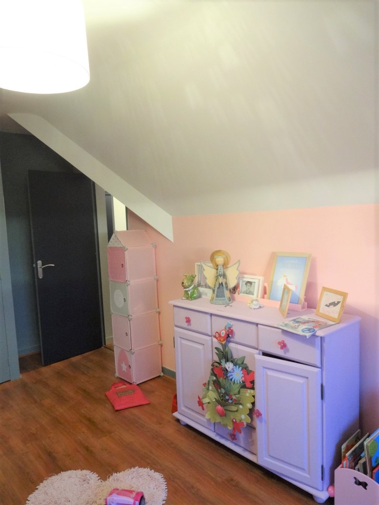 Cette image montre une chambre d'enfant minimaliste avec un mur rose et un sol marron.