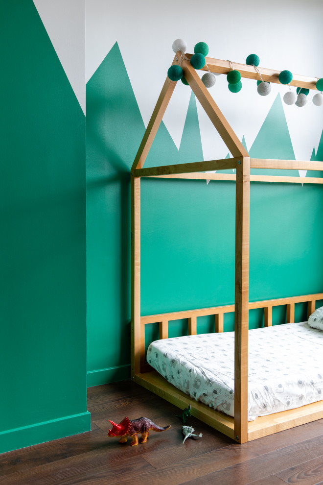 Contemporary children’s room for boys in Paris with green walls, dark hardwood flooring and brown floors.