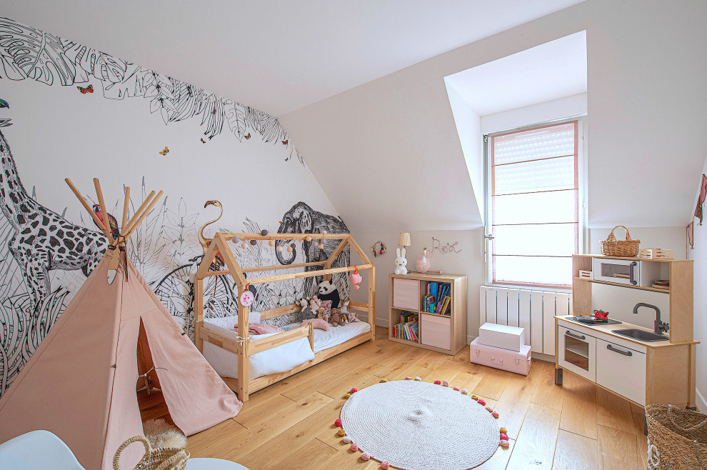 Immagine di una cameretta per bambini da 1 a 3 anni minimal con pareti bianche, pavimento in legno massello medio, pavimento marrone e carta da parati