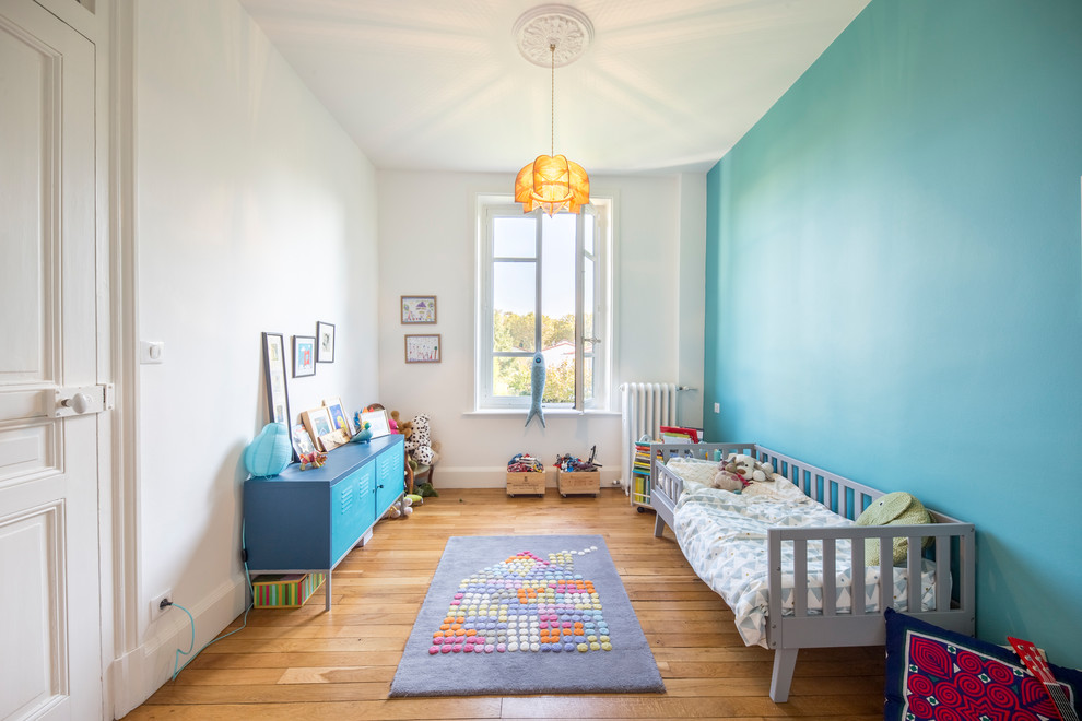 Aménagement d'une chambre d'enfant de 4 à 10 ans classique de taille moyenne avec un mur bleu, un sol marron et un sol en bois brun.