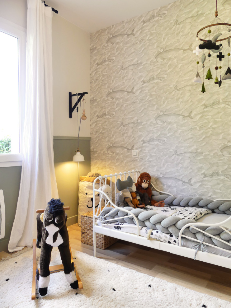 Modelo de dormitorio infantil de 1 a 3 años costero de tamaño medio con paredes verdes, suelo de madera clara, suelo marrón y papel pintado