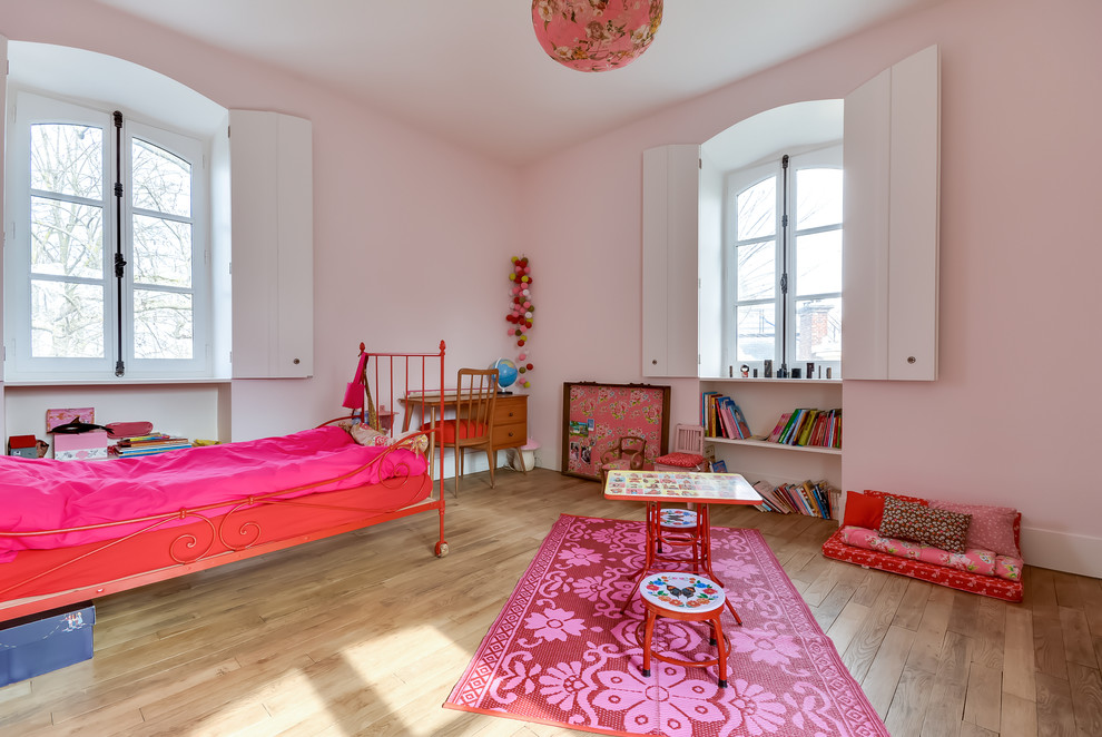 Bild på ett stort eklektiskt flickrum kombinerat med sovrum och för 4-10-åringar, med rosa väggar och mellanmörkt trägolv