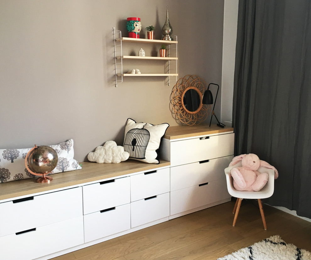Foto på ett mellanstort skandinaviskt könsneutralt småbarnsrum kombinerat med sovrum, med ljust trägolv, bruna väggar och brunt golv