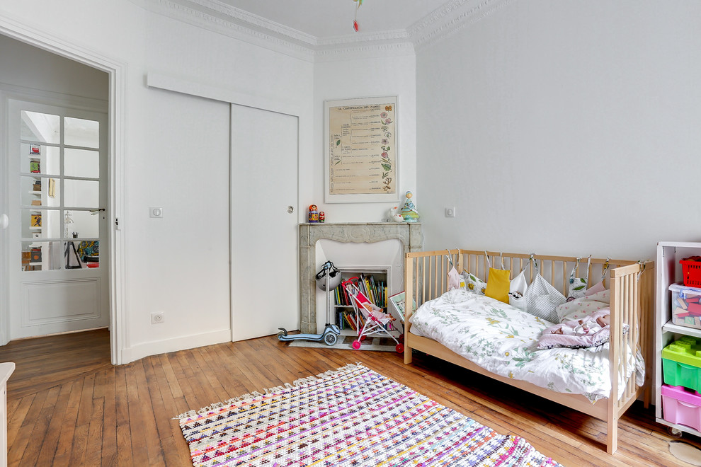 Esempio di una cameretta per bambini da 1 a 3 anni scandinava con pareti bianche, pavimento in legno massello medio e pavimento marrone