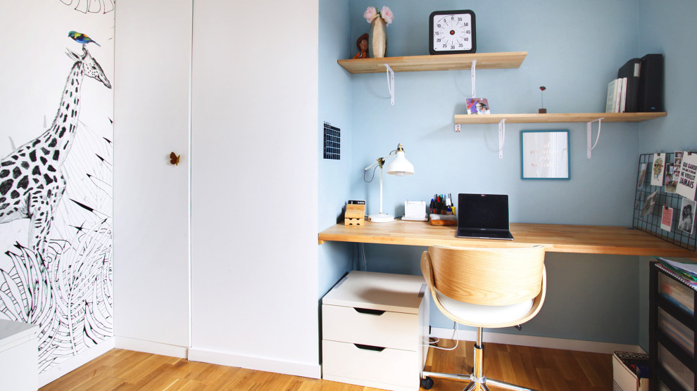 Cette image montre une chambre de garçon design de taille moyenne avec un bureau, un mur bleu, parquet clair, un sol marron et du papier peint.