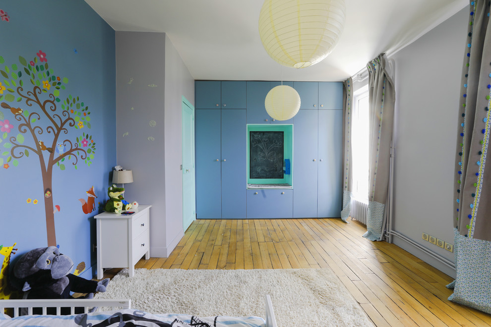 Immagine di una grande cameretta per bambini da 4 a 10 anni contemporanea con pareti blu, parquet chiaro e pavimento marrone