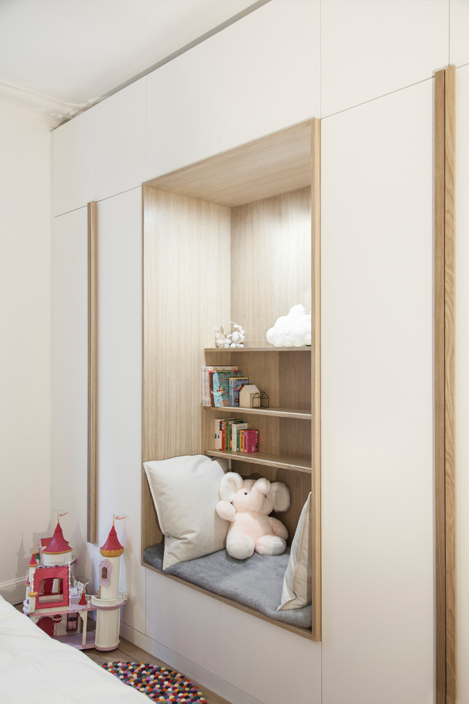 Modern inredning av ett mellanstort könsneutralt barnrum kombinerat med sovrum och för 4-10-åringar, med vita väggar, mellanmörkt trägolv och beiget golv