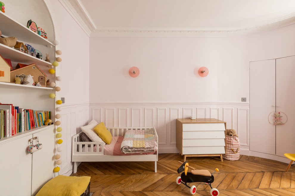 Cette image montre une chambre d'enfant design avec un mur rose et un sol en bois brun.