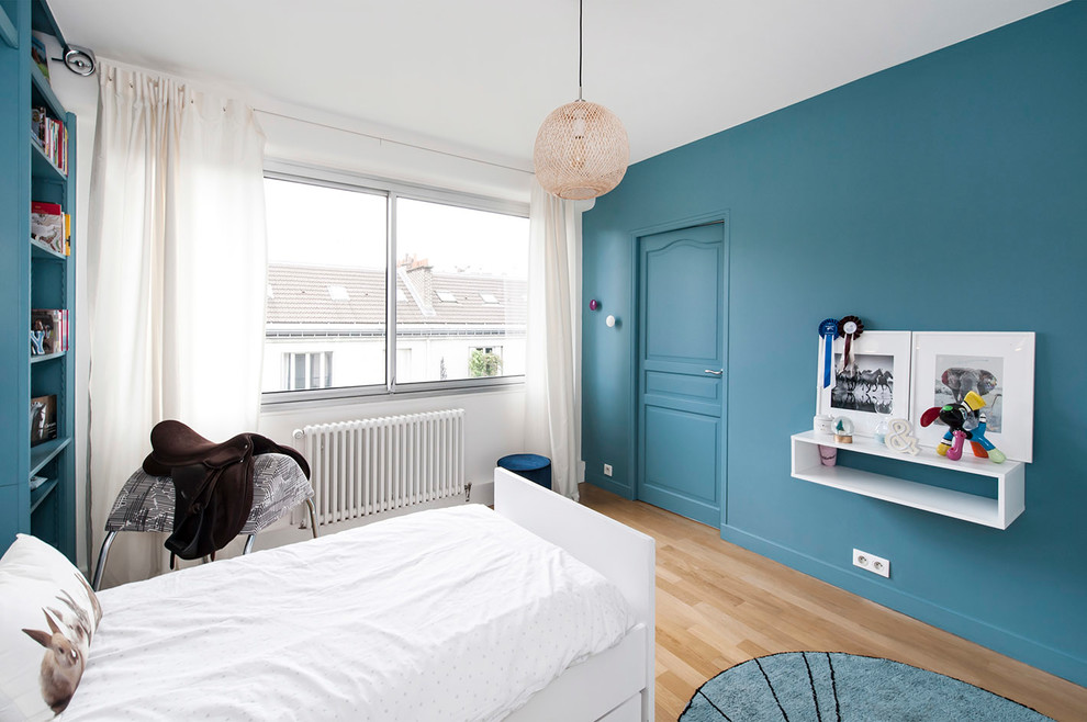Large contemporary gender neutral teen’s room in Paris with blue walls, laminate floors and beige floors.