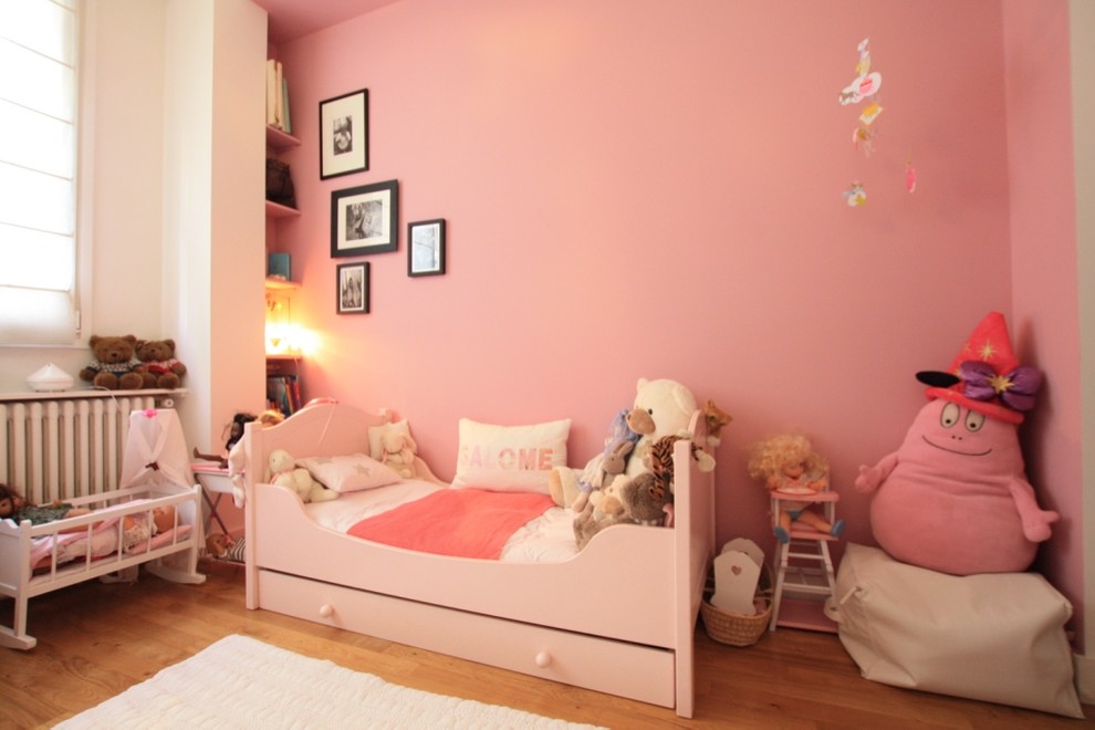 Cette image montre une chambre d'enfant traditionnelle avec un mur rose et parquet clair.