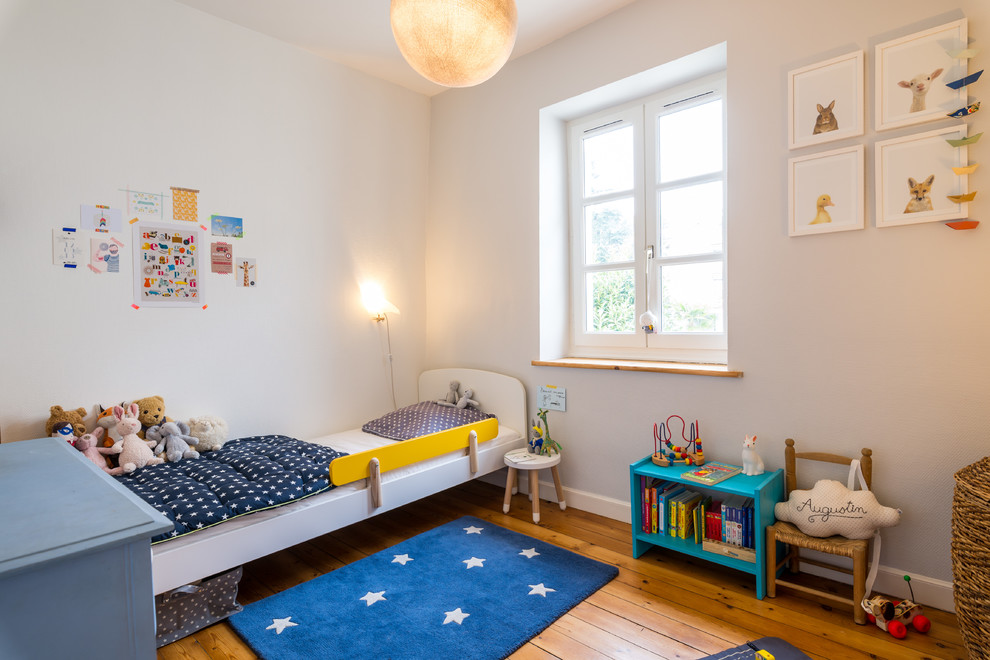 Diseño de dormitorio infantil de 1 a 3 años escandinavo de tamaño medio con paredes blancas y suelo de madera en tonos medios