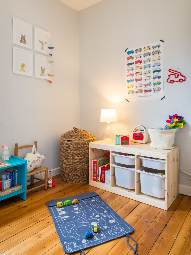 Exemple d'une chambre d'enfant de 1 à 3 ans scandinave avec un mur blanc et un sol en bois brun.