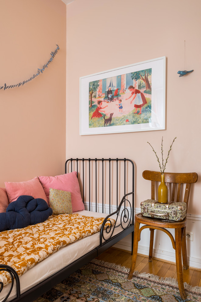 Idée de décoration pour une chambre d'enfant de 4 à 10 ans nordique de taille moyenne avec un mur rose et un sol en bois brun.