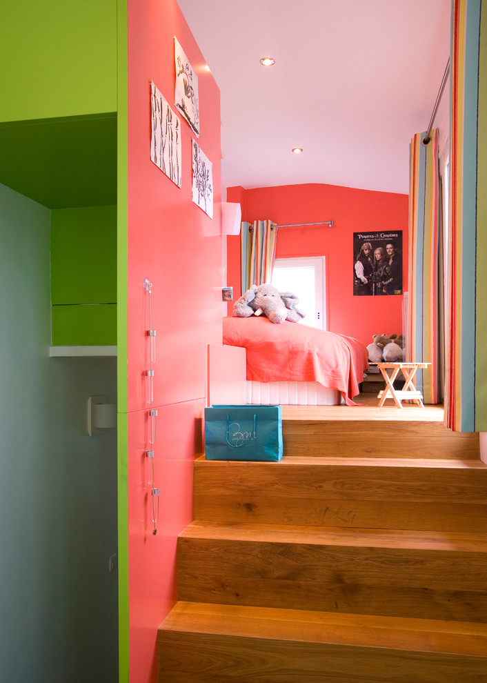 Modern inredning av ett stort könsneutralt barnrum kombinerat med sovrum och för 4-10-åringar, med rosa väggar och mellanmörkt trägolv