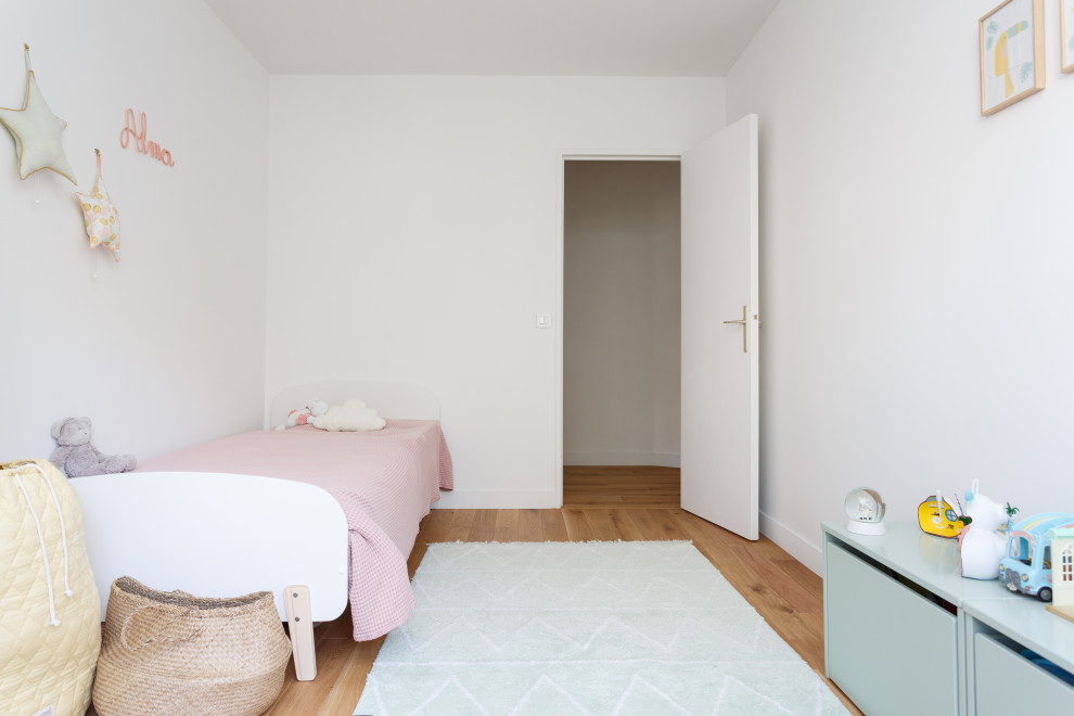Design ideas for a medium sized scandi children’s room for girls in Paris with white walls, light hardwood flooring and beige floors.