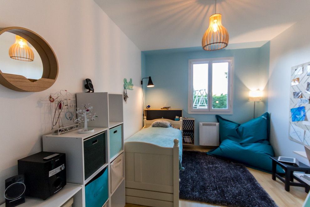 Modelo de dormitorio infantil contemporáneo pequeño con paredes azules, suelo de madera clara y suelo marrón