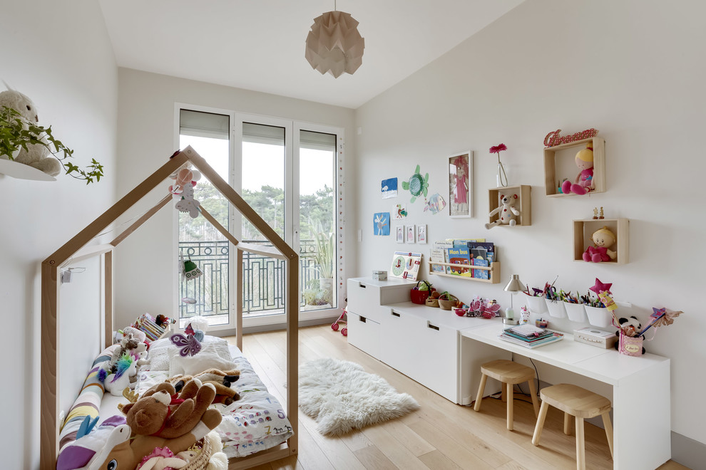 Design ideas for a scandinavian children’s room for girls in Paris with grey walls, light hardwood flooring, beige floors and feature lighting.