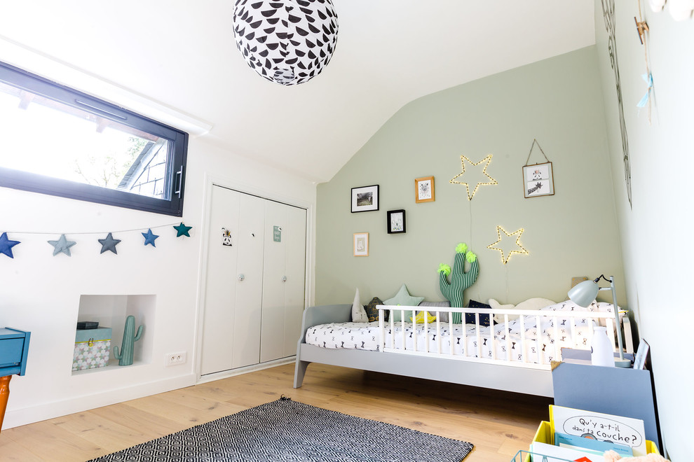 Cette photo montre une chambre d'enfant de 1 à 3 ans tendance de taille moyenne avec un mur vert, parquet clair et un sol marron.