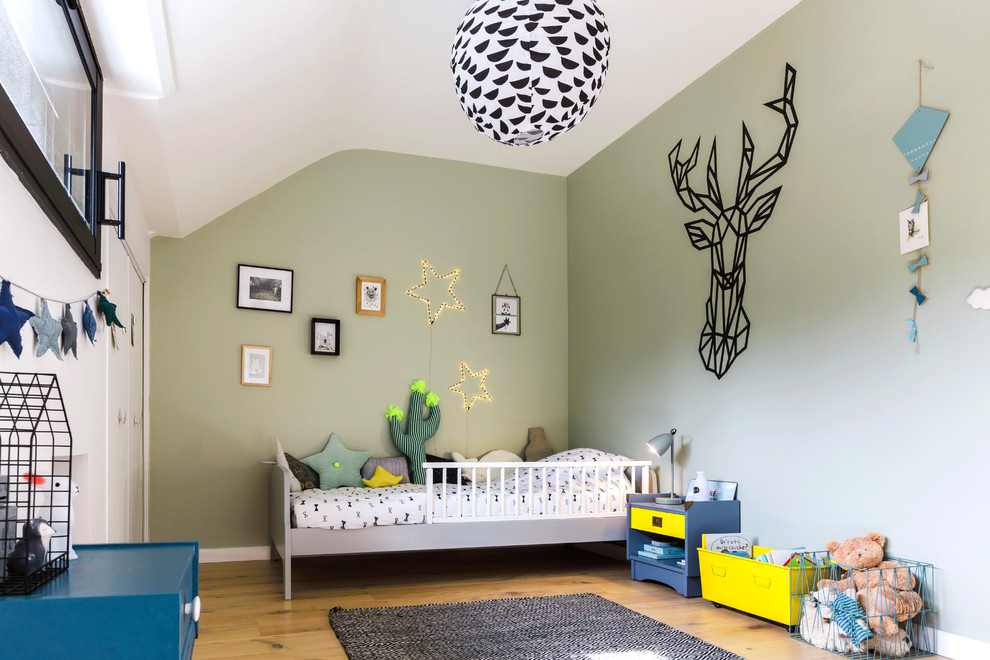 Idée de décoration pour une chambre d'enfant de 1 à 3 ans design de taille moyenne avec un mur vert, parquet clair et un sol marron.