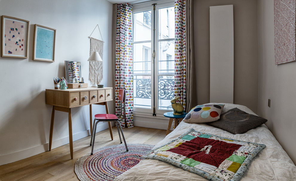 Idéer för att renovera ett mellanstort funkis flickrum kombinerat med sovrum och för 4-10-åringar, med beige väggar och ljust trägolv