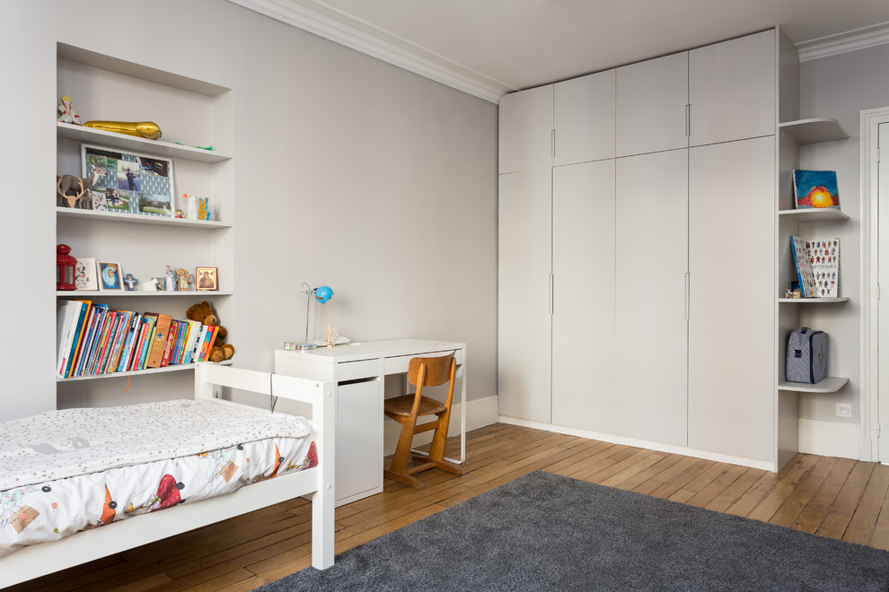 Immagine di una cameretta per bambini da 4 a 10 anni contemporanea di medie dimensioni con pareti bianche, pavimento beige e pavimento in legno massello medio