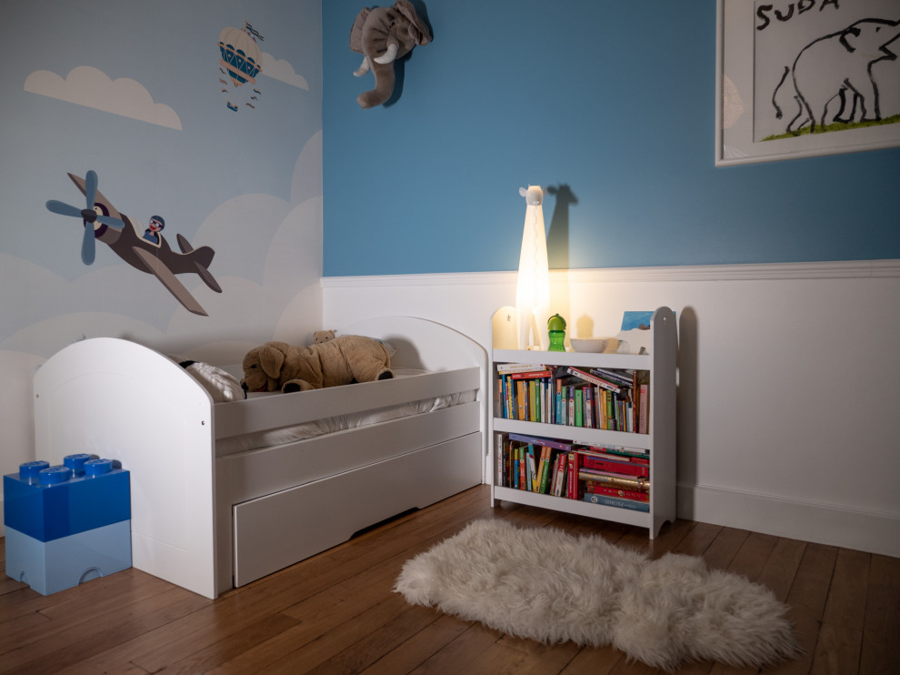 Inspiration för ett mellanstort vintage könsneutralt småbarnsrum kombinerat med sovrum, med blå väggar och ljust trägolv