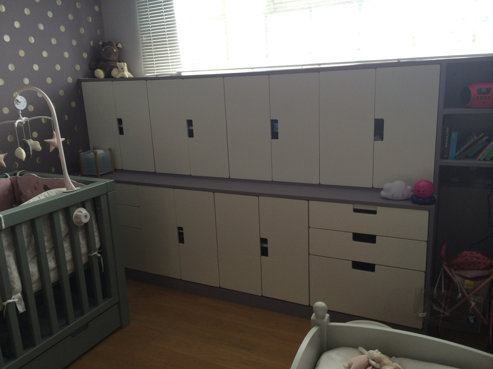 Cette image montre une chambre de bébé fille design de taille moyenne avec un mur violet et parquet clair.
