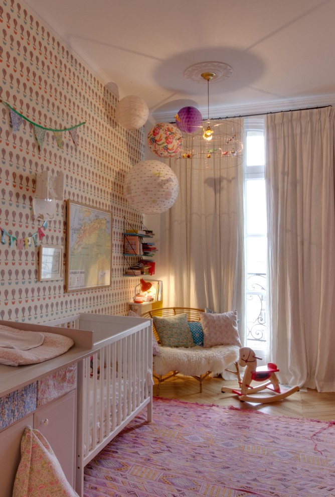 Minimalistisk inredning av ett babyrum, med flerfärgade väggar, ljust trägolv och beiget golv