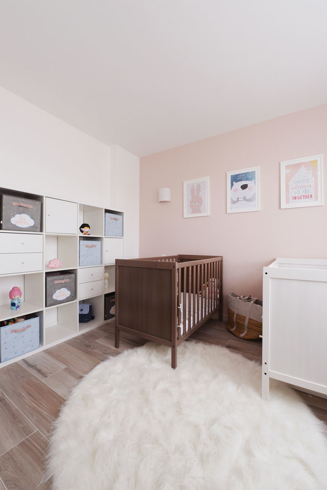 Cette image montre une chambre de bébé fille nordique avec un mur rose et un sol beige.