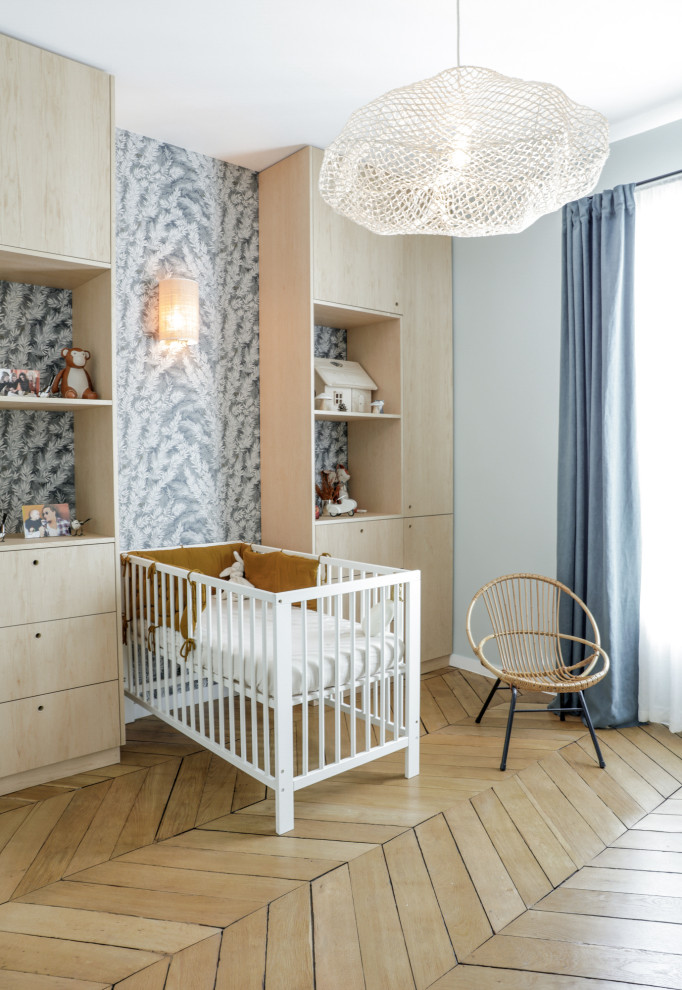 Neutrales Nordisches Babyzimmer mit grauer Wandfarbe, braunem Holzboden, braunem Boden und Tapetenwänden in Paris