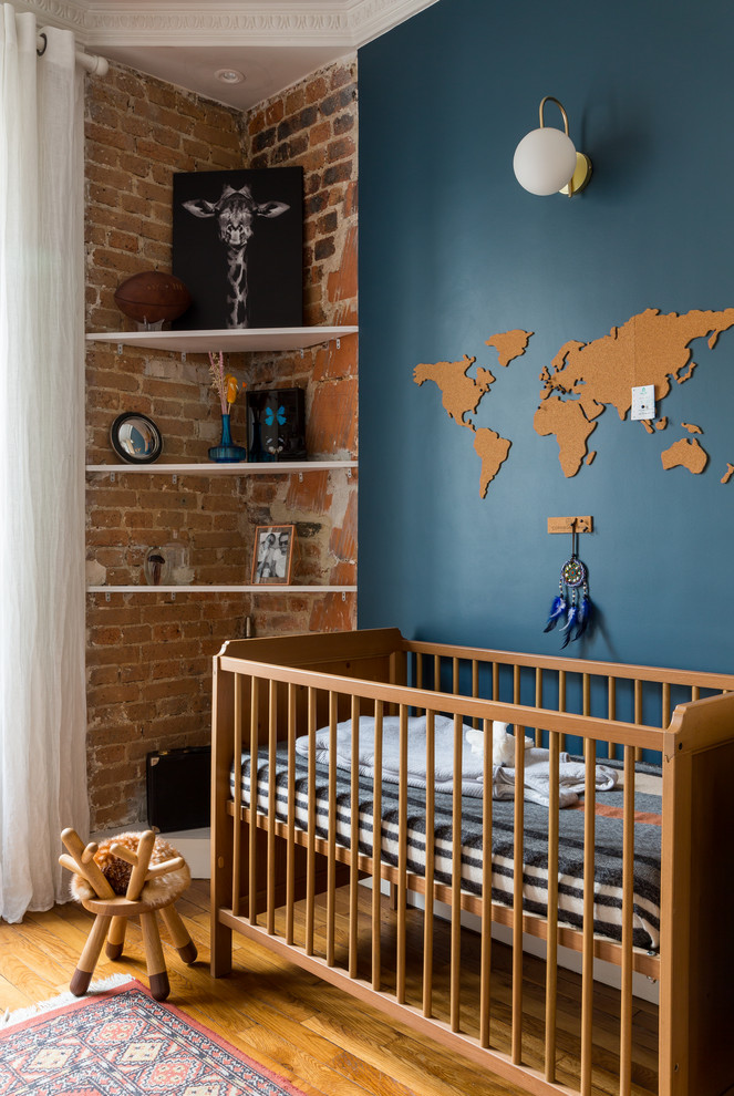 Immagine di una cameretta per neonati nordica con pareti blu, pavimento in legno massello medio e pareti in mattoni