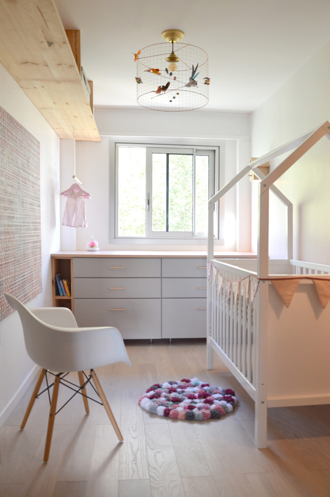 Réalisation d'une chambre de bébé style shabby chic avec un mur rose et parquet clair.