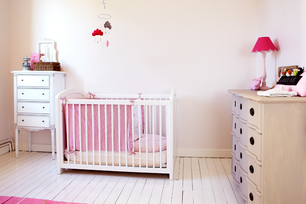 Cette image montre une chambre de bébé fille traditionnelle de taille moyenne avec un mur blanc et parquet peint.