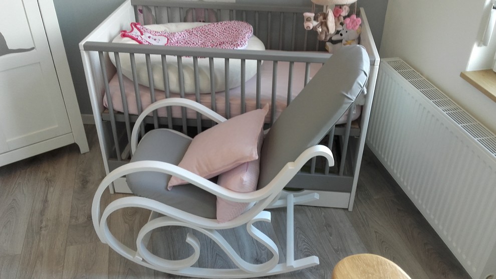 Modelo de habitación de bebé niña contemporánea pequeña con paredes grises, suelo laminado y suelo gris