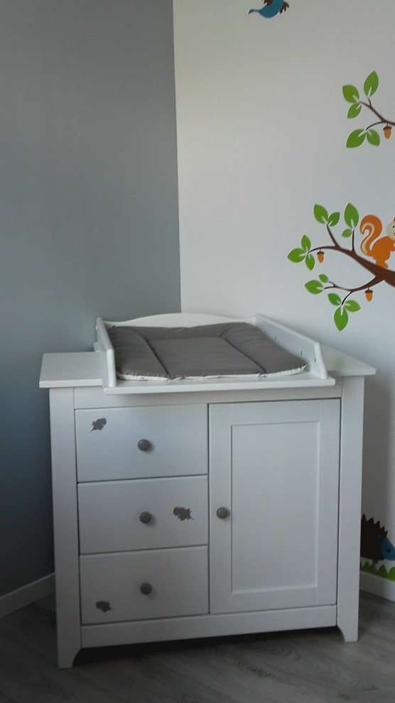 Modelo de habitación de bebé niña actual pequeña con paredes grises, suelo laminado y suelo gris