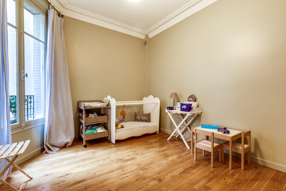 Imagen de habitación de bebé neutra clásica renovada de tamaño medio con paredes beige y suelo de madera clara