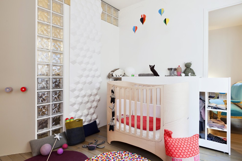 Foto de habitación de bebé neutra actual de tamaño medio con paredes blancas y suelo de madera clara