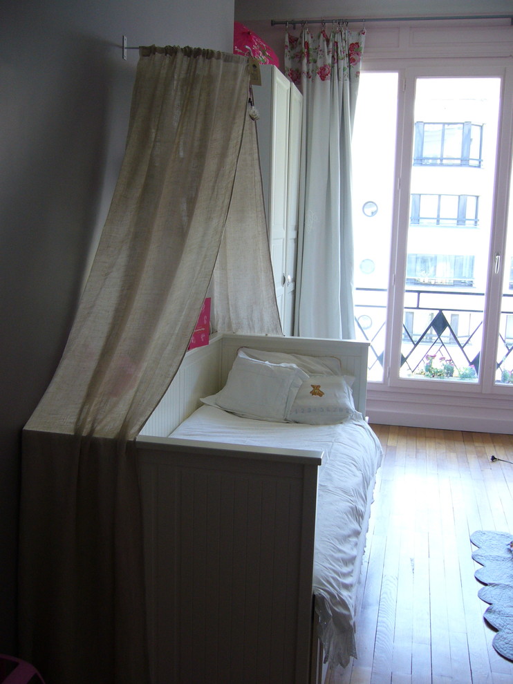Exemple d'une grande chambre de bébé fille éclectique avec un mur beige, parquet clair et un sol beige.