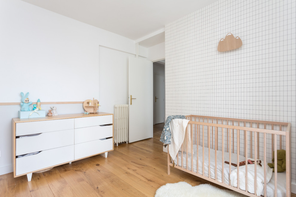 Foto de habitación de bebé neutra escandinava de tamaño medio con paredes blancas, suelo de madera clara, suelo beige y papel pintado