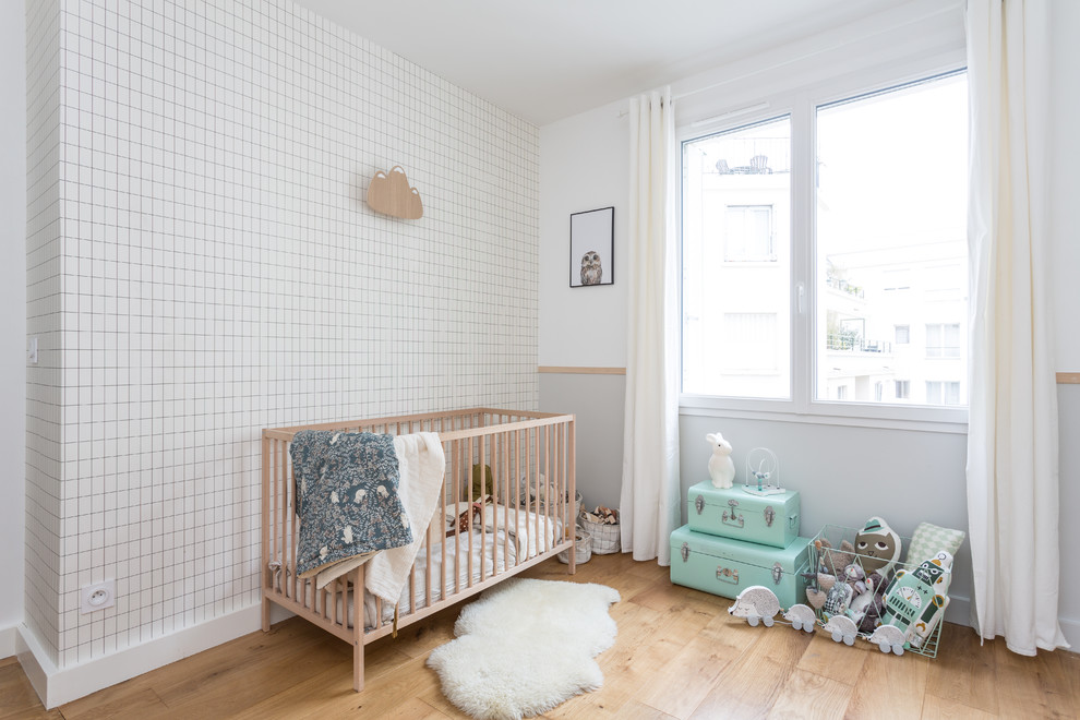 Idées déco pour une chambre de bébé neutre scandinave de taille moyenne avec un mur multicolore, un sol en bois brun et un sol beige.